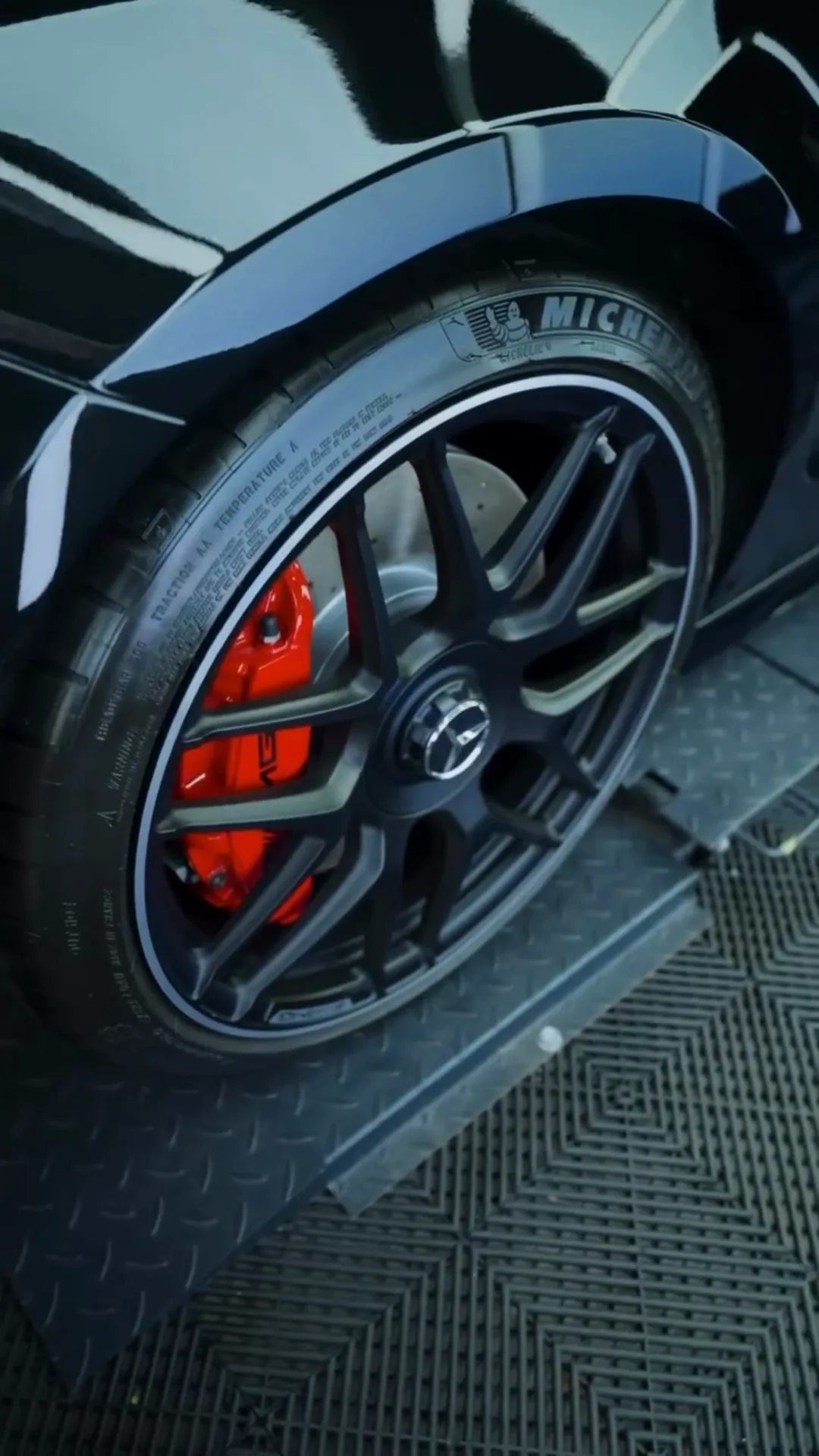 Glossy black wheel and red brake caliper on a Mercedes-AMG