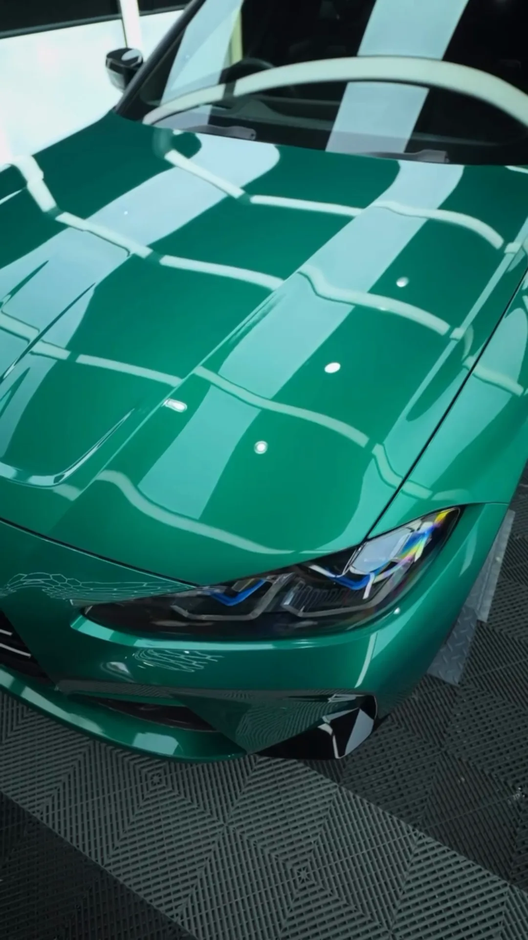 Green BMW M4 bonnet holding a mirror finish under studio lights